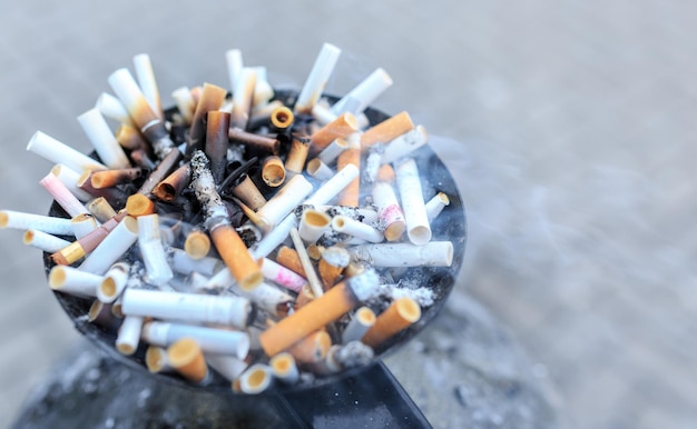 Cigarette butts at ashtray. close up heap of many smoking cigarettes stubs, cigarette butts in ashtray