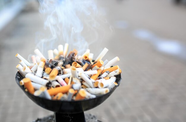 Cigarette butts at ashtray. Close up heap of many smoking cigarettes stubs, cigarette butts in ashtray