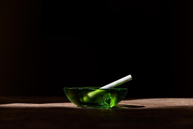 Cigarette in a green ashtray black background nicotine addictions