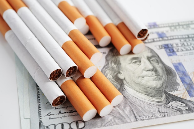 Cigarette on US dollar banknotes cost trading marketing and production No smoking concept