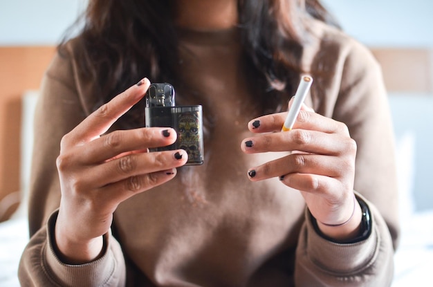 Cigarette vs e-cigarette concept. woman holding cigarette and vape. best for healtcare background