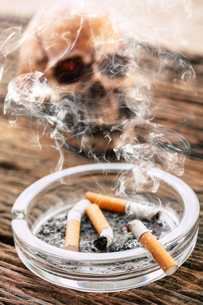 cigarette with model skull on wooden table