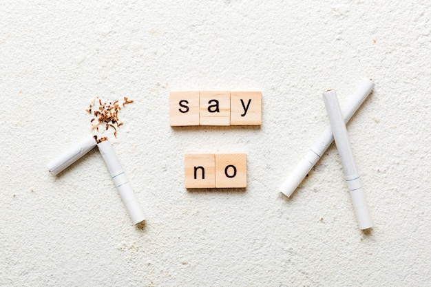 Cigarette And Wooden Blocks Broken cigarette on table background No Tobacco Day with hourglass clock health concept time to quit smoking