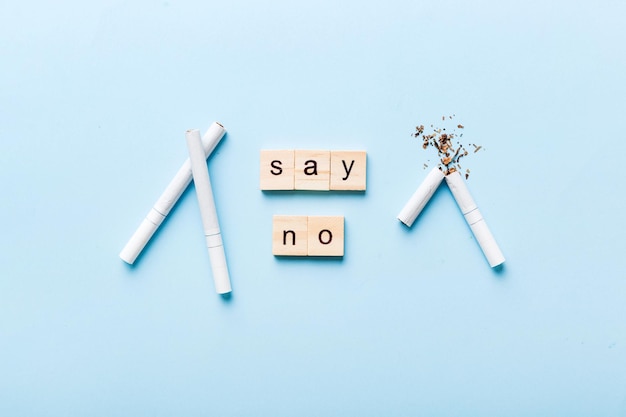 Cigarette And Wooden Blocks Broken cigarette on table background No Tobacco Day with hourglass clock health concept time to quit smoking