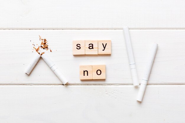 Cigarette And Wooden Blocks Broken cigarette on table background No Tobacco Day with hourglass clock health concept time to quit smoking