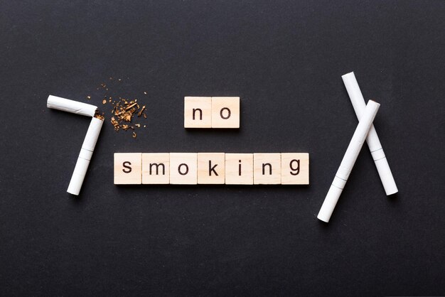 テーブルの背景にタバコと木のブロックが壊れたタバコ砂時計時計健康コンセプトの禁煙日喫煙をやめる時間