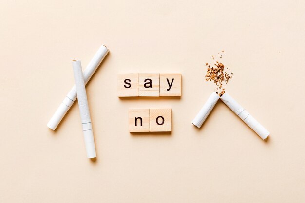 Cigarette And Wooden Blocks Broken cigarette on table background No Tobacco Day with hourglass clock health concept time to quit smoking