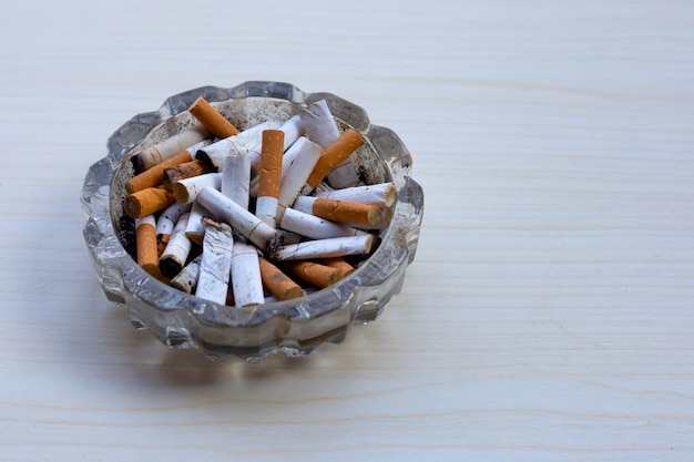 Cigarettes buds in a transparent ashtray on table