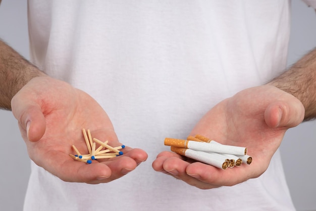 cigarettes and matches in male hands on a light background