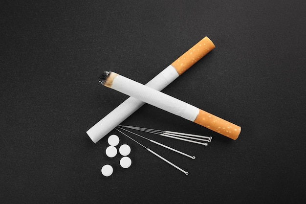 Cigarettes with needles and pills on table