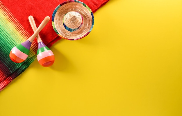 Cinco de mayo holiday background made from maracas mexican blanket stripes or poncho serape and hat on yellow background