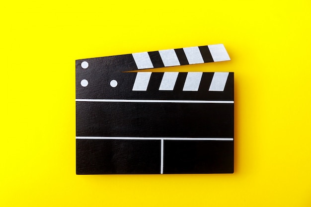 Cinema black clapperboard on yellow background. Modern cinematography, filmmaking.