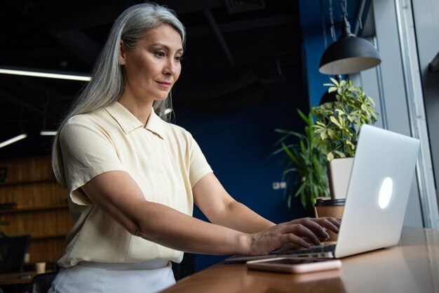 Cinematic image of a senior  business woman. Portrait of an employee in her office