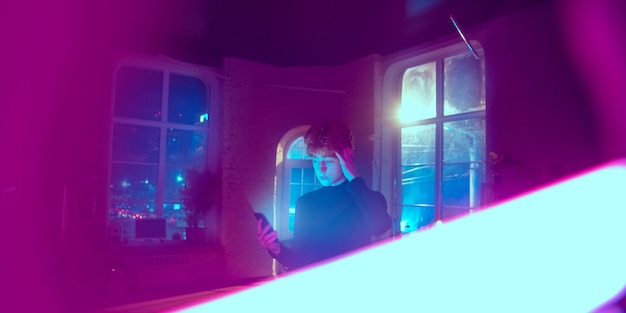 Cinematic portrait of handsome young man in neon lighted interior