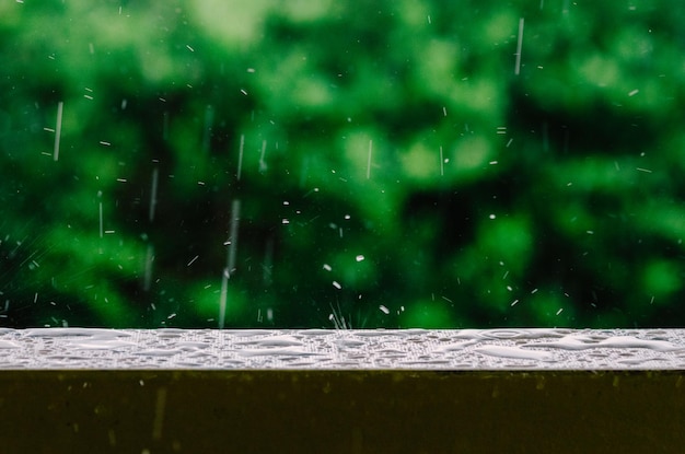 Photo cinematic shot of raindrops falling from the grey skies and onto the wet surface of a balcony railing creating ripples in the still water