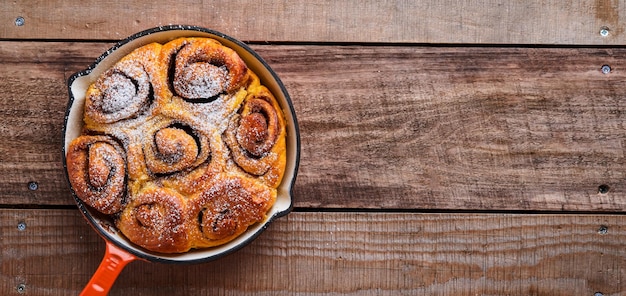 Cinnabon cinnamon rolls buns with pumpkin nut caramel and sugar cream iced on rustic wooden background table Top view Sweet Homemade Pastry christmas baking Kanelbule swedish dessert