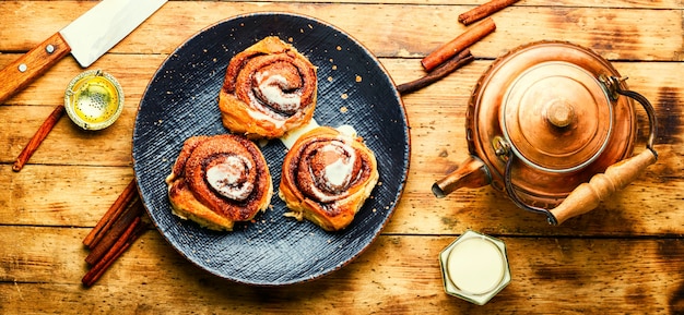 Cinnabones with cinnamon and mascarpone cheese.Homemade buns on a plate.Cinnamon rolls or cinnabon