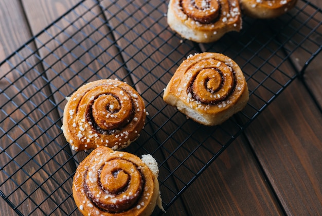 Cinnabons won a wire rack on the table. Food concept. Homemade sweet pastries on a wooden background. Top view