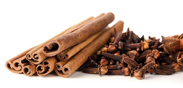 Cinnamon dry sticks and cloves spice pile isolated on white background