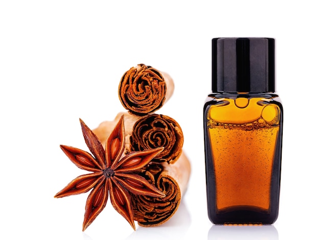 Cinnamon essential oil bottle with Ceylon cinnamon sticks and anise star isolated on white .