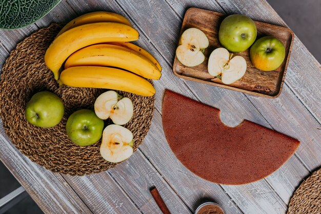 Cinnamon fruit leather with fresh fruits on the wooden table. Round fruit leather. Healthy food. Apples, bananas and cinnamon sticks top view.