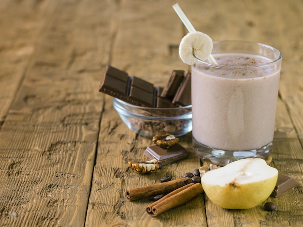 Cinnamon, pear and chocolate smoothie on a wooden table.