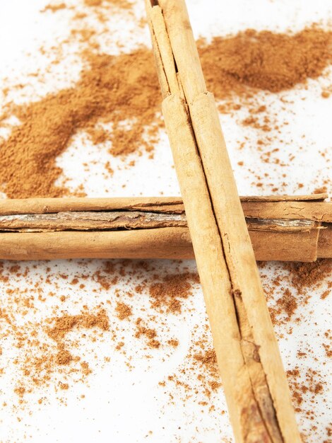 Cinnamon powder and sticks on a white background