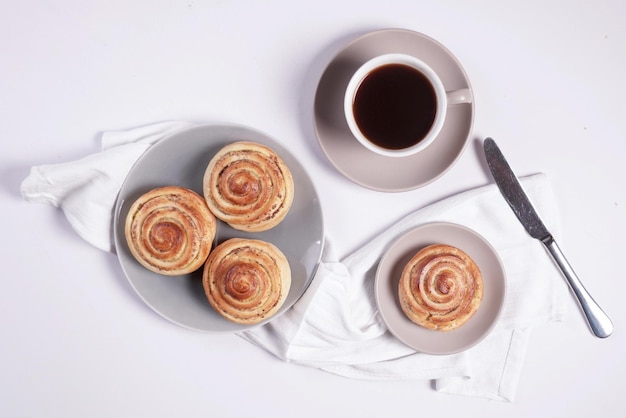 Cinnamon roll with americano coffee cup top view in white background