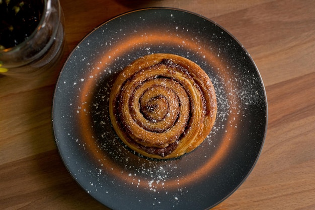 Cinnamon rolls on a black plate on a wooden table top view