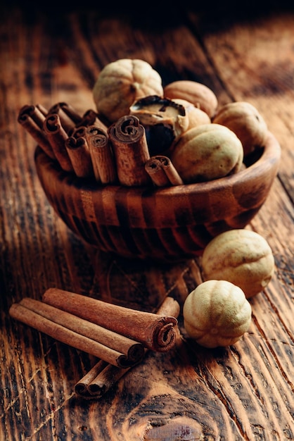 Фото Палочки корицы и сушеные лаймы в деревянной миске на деревенском столе