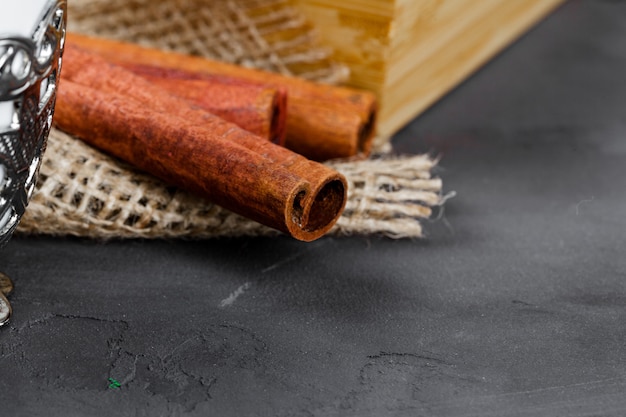 Cinnamon sticks on black textured surface close up