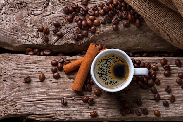 Bastoncini di cannella e tazza di caffè. chicchi di caffè tostati vicino alla borsa. bevanda aromatica dal gusto specifico. per gli amanti dell'espresso.