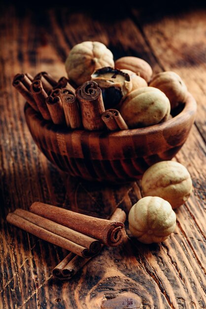 Foto bastoncini di cannella e lime essiccati in una ciotola di legno su un tavolo rustico