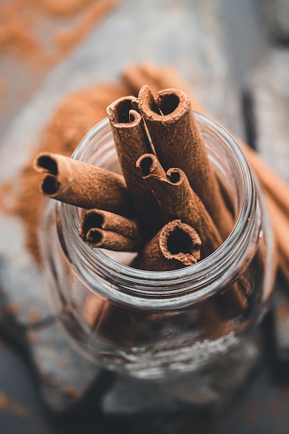 Photo cinnamon sticks in a glass jar on black background