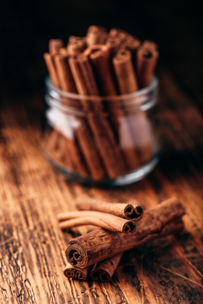 Cinnamon sticks in a glass jar over rustic wooden surface