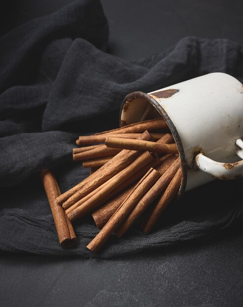 Фото Коричневые палочки в старой металлической чашке на черном столе ароматические специи