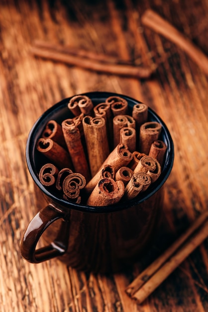 Photo cinnamon sticks in a metal mug on rustic wooden surface