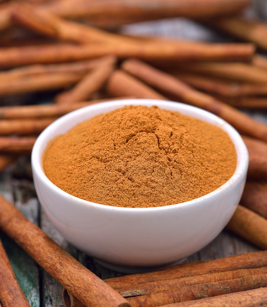 Cinnamon sticks and powder cinnamon in the bowl on table