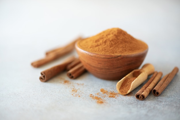 Cinnamon sticks and powder on grey background. Spices for ayurvedic treatment. 