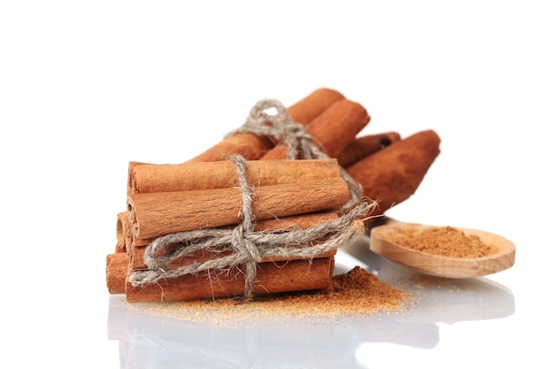 Cinnamon sticks and powder in wooden spoon isolated on white