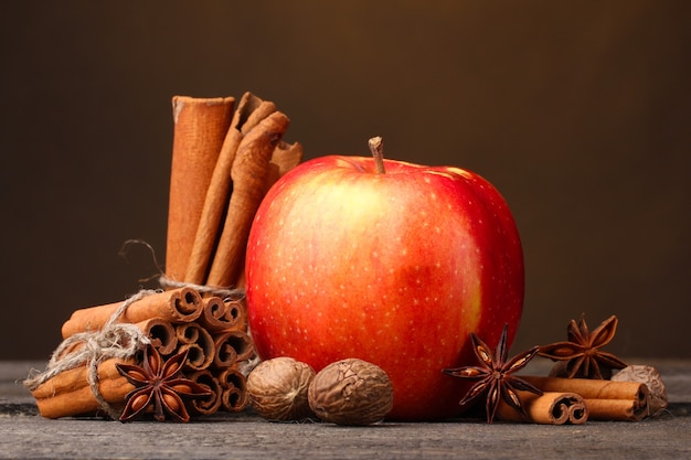 Cinnamon sticks,red apple, nutmeg,and anise on wooden table