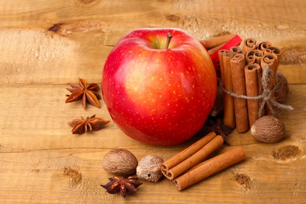 Cinnamon sticks,red apple, nutmeg,and anise on wooden table