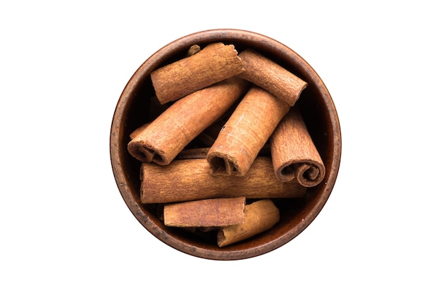 Cinnamon sticks spice in wooden bowl, isolated on white background. Seasoning top view