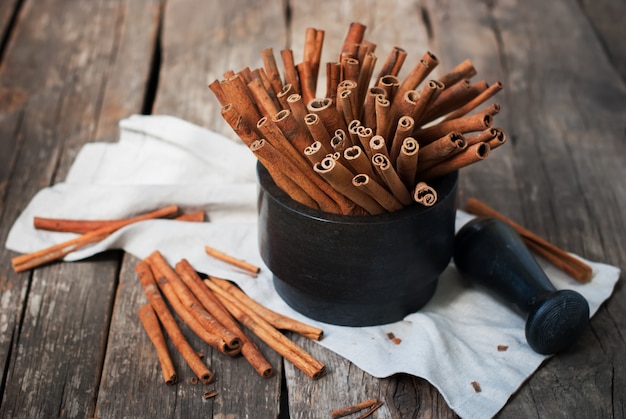 Cinnamon Sticks in a Stone Mortar on Wooden Country Background