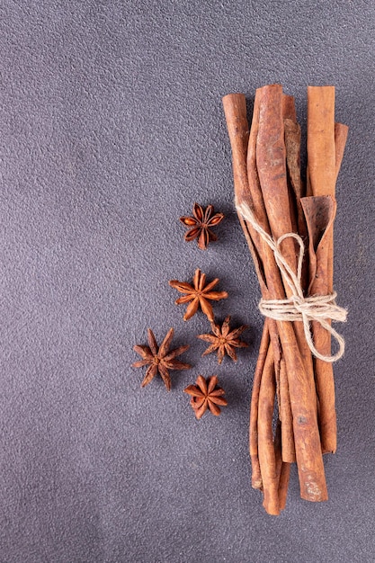Cinnamon sticks tied with coarse rope star anise on a blue background copy space