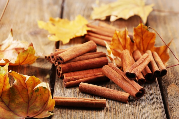 Cinnamon sticks with yellow leaves on wooden background