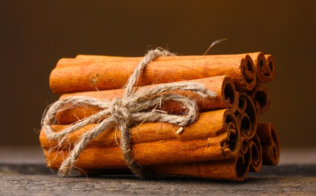 Cinnamon sticks on wooden table on brown surface