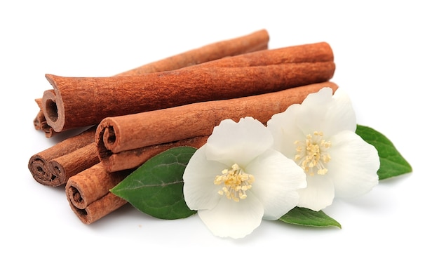 Cinnamon with flowers isolated on white.