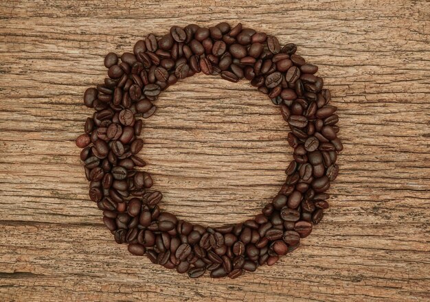 Circle frame made of coffee beans on wooden background View from above Coffee background