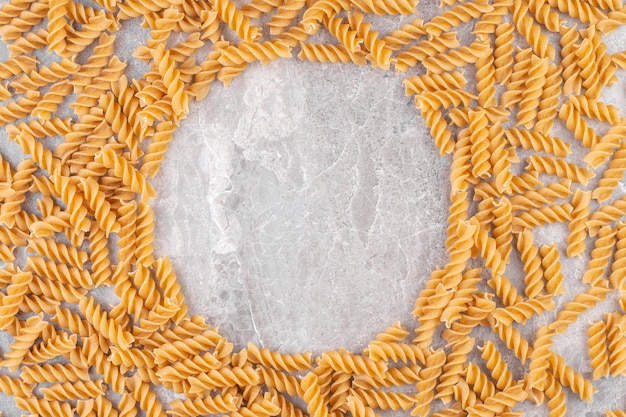 Circle of raw dry spiral pasta on a stone .